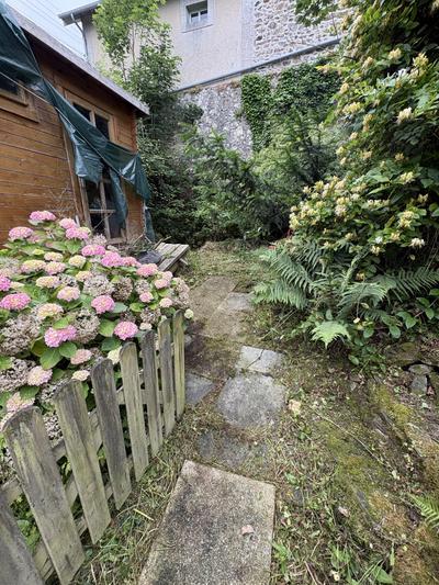 Chemin dallé vers le cabanon dégagé des herbes folles et des massifs envahis — après