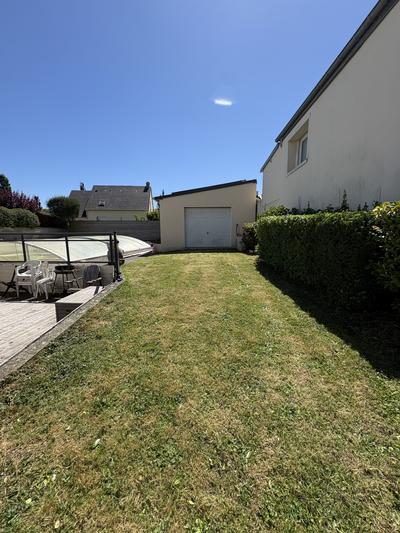 Pelouse tondue avec terrasse en bois et véranda en arrière-plan